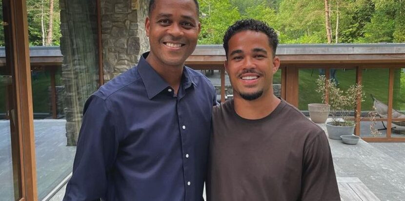 Patrick Kluivert dan putranya Justin Kluivert berpose bersama di luar rumah, tersenyum ke arah kamera.