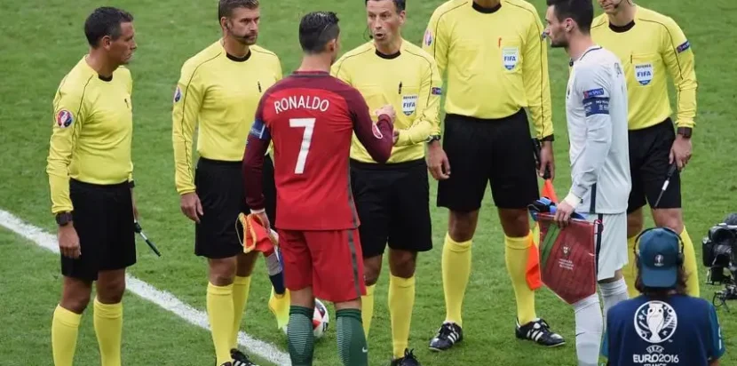 Mark Clattenburg memimpin Final EURO 2016 antara Portugal dan Prancis, berdiri bersama Cristiano Ronaldo dan Hugo Lloris.