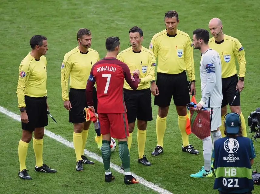 Mark Clattenburg memimpin Final EURO 2016 antara Portugal dan Prancis, berdiri bersama Cristiano Ronaldo dan Hugo Lloris.