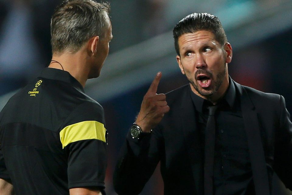 Diego Simeone menunjuk wasit dengan ekspresi kesal di pinggir lapangan.