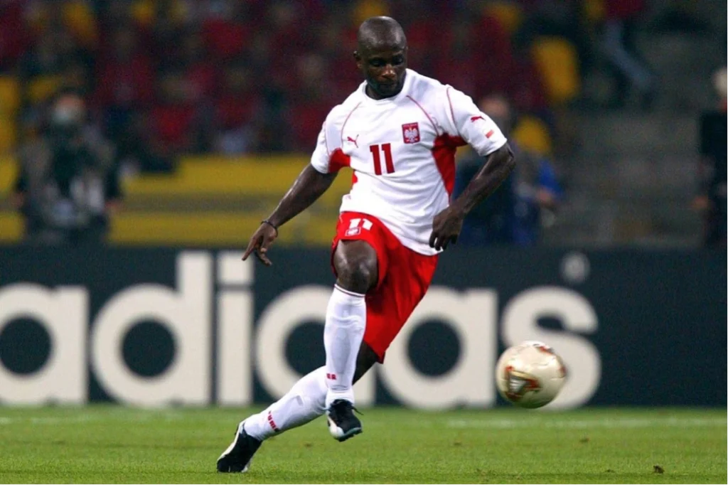 Emmanuel Olisadebe melakukan tendangan saat bermain untuk Timnas Polandia.