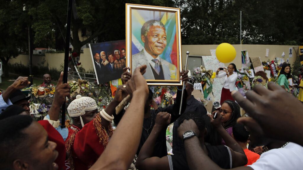 Para pendukung Nelson Mandela berkumpul sambil membawa potret besar sang pemimpin Afrika Selatan setelah kabar wafatnya tahun 2013.
