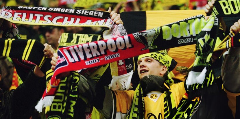 Fans Borussia Dortmund dan Liverpool mengangkat syal gabungan kedua klub, menunjukkan persaudaraan mereka lewat lagu You'll Never Walk Alone.