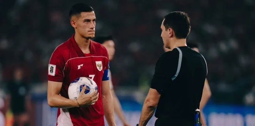 Jay Idzes mengenakan ban kapten Timnas Indonesia berbicara dengan wasit di tengah lapangan.