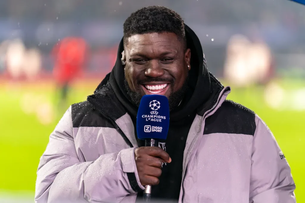 Royston Drenthe tersenyum saat menjadi pundit sepak bola di siaran Champions League