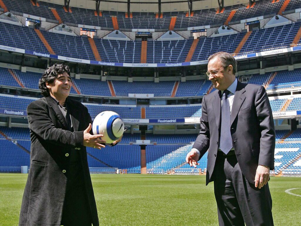 Diego Maradona dan Florentino Perez berbincang sambil memegang bola di Santiago Bernabeu.