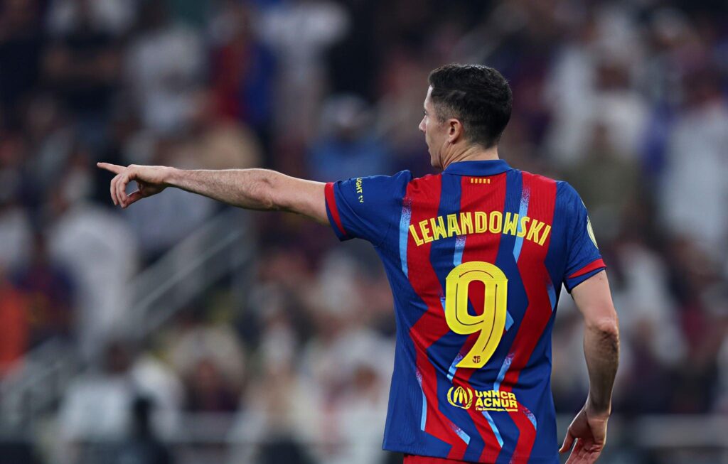 Robert Lewandowski menunjuk ke depan saat membela Barcelona, termasuk dalam daftar penjualan jersey terbanyak 2025.